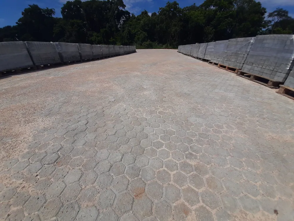 Área pavimentada com pavers intertravados, ladeada por muros